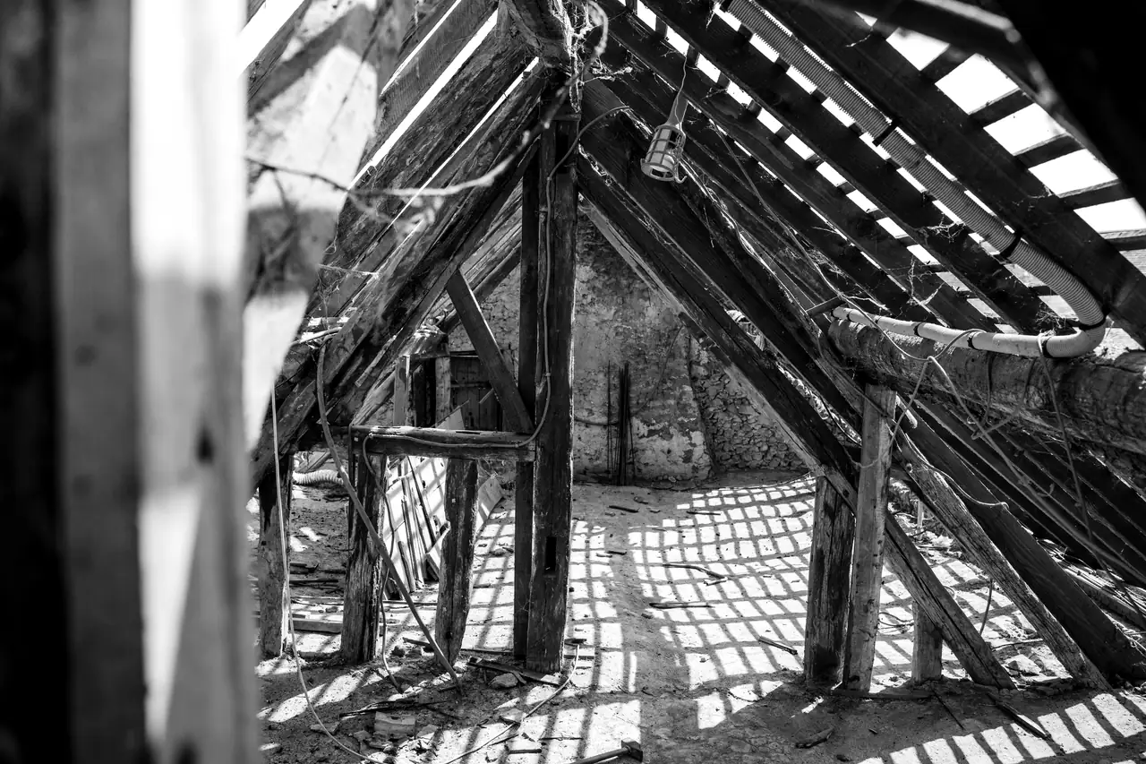 Combles anciens : charpente en bois, plancher et lumière rasante