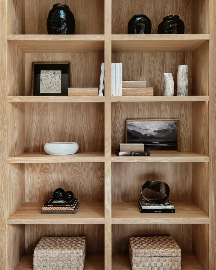 Une bibliothèque en chêne clair, avec des objets posés sur les étagères.