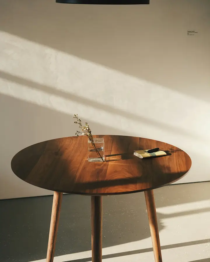 Une table ronde en noyer dans la lumière du soleil.
